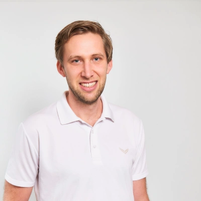 Lächelnder Mann in weißem Polohemd vor hellem Hintergrund